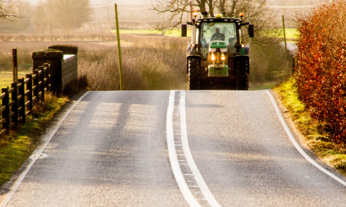 Green tractor on a sunlit rural road — local delivery across North Alabama