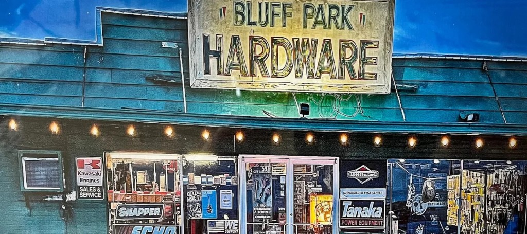 Vintage blue Bluff Park Hardware storefront with a weathered sign, warm string lights, and windows displaying tools, brands, and supplies.