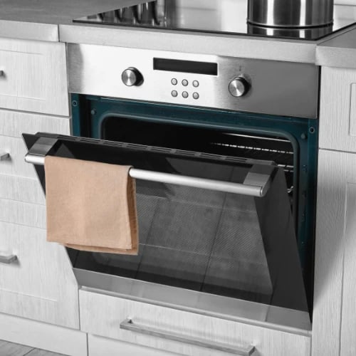 A modern stainless-steel oven is open in a bright kitchen, with a beige towel draped over its handle; the clean, orderly scene feels calm and practical.