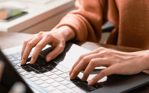 Hands typing on a laptop