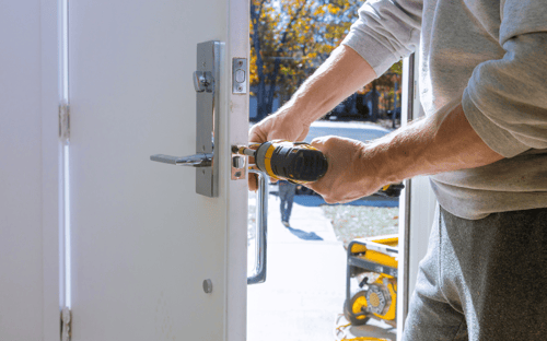 A close up of a door lock being installed with a power drill