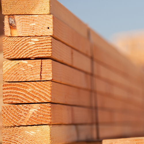 Stack of neatly arranged, light brown wooden planks showing natural wood grain and textures