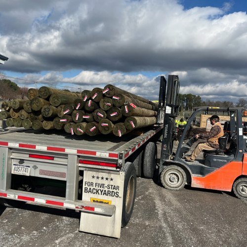 A truck stacked with lumber being loaded with a forklift outside of S&S Wholesale warehouse