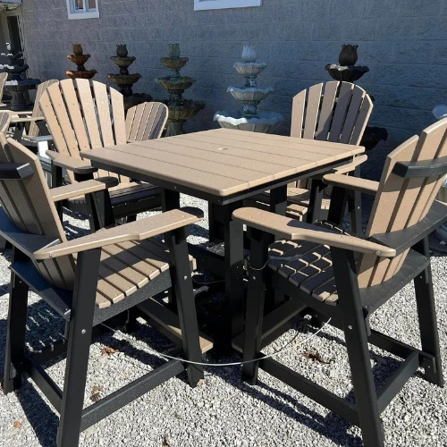 Outdoor patio dining set with a square table and four slatted wooden chairs, displayed on gravel against a gray wall in bright sunlight.