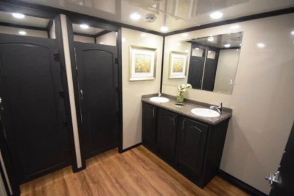 A narrow bathroom with a pale vanity and sink at left, while several dark, paneled doors stand partly open, creating a shadowy, cramped view.